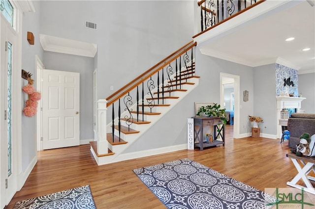 foyer entrance with a high ceiling, hardwood / wood-style floors, and crown molding