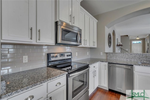 kitchen featuring appliances with stainless steel finishes, white cabinets, backsplash, and light stone countertops