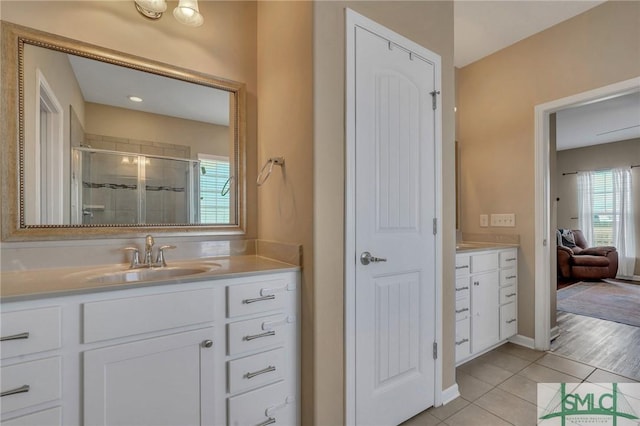 bathroom with a healthy amount of sunlight, walk in shower, tile patterned flooring, and vanity