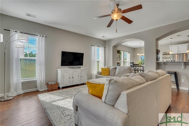 living room featuring ceiling fan with notable chandelier, plenty of natural light, and dark hardwood / wood-style floors