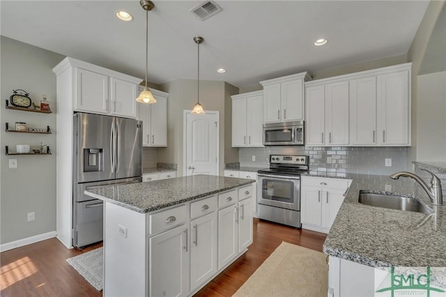 kitchen featuring appliances with stainless steel finishes, white cabinets, sink, and a kitchen island