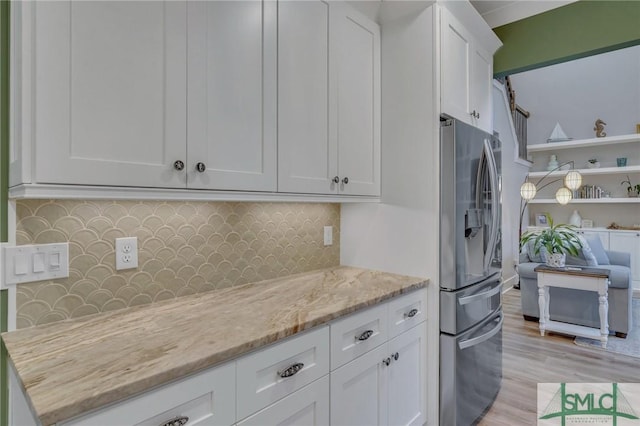 kitchen featuring tasteful backsplash, light stone countertops, stainless steel fridge with ice dispenser, light wood-style floors, and white cabinetry