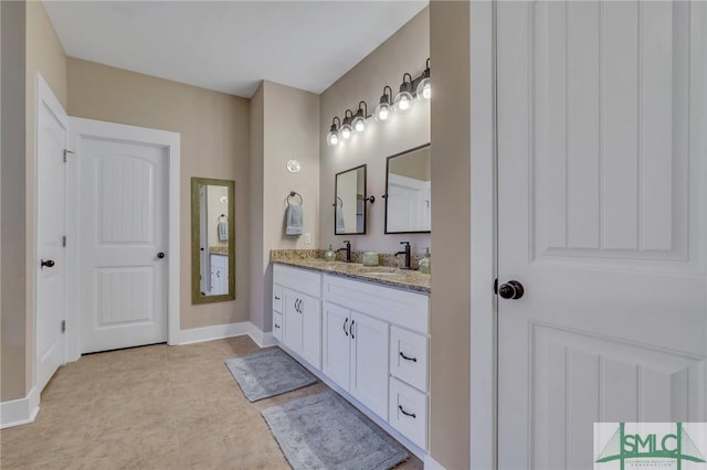 bathroom featuring double vanity, baseboards, and a sink