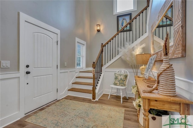 foyer entrance with stairway, a healthy amount of sunlight, a decorative wall, and wood finished floors