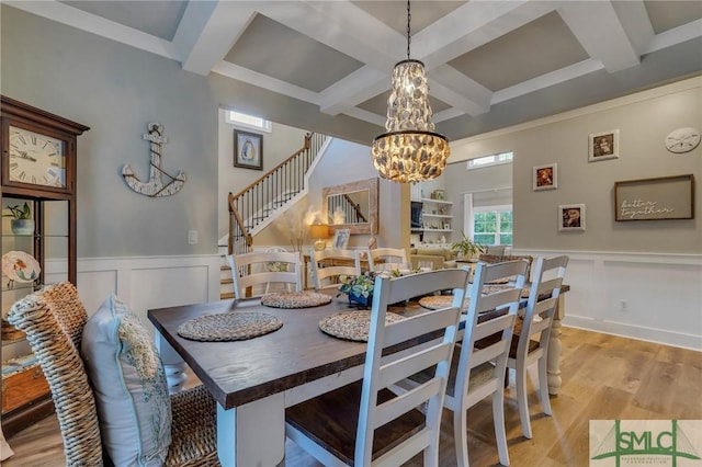 dining space featuring stairway, beam ceiling, light wood-style floors, and a chandelier