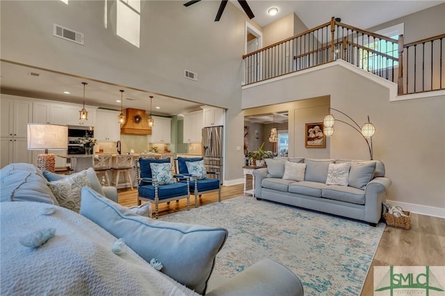 living area with light wood-style flooring, baseboards, visible vents, and ceiling fan