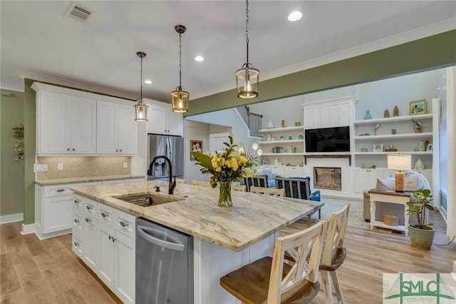 kitchen featuring visible vents, ornamental molding, appliances with stainless steel finishes, white cabinetry, and a sink