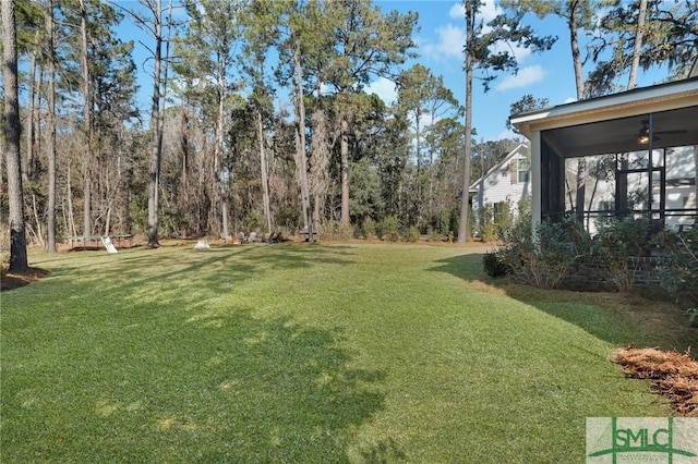 view of yard with a ceiling fan and a sunroom