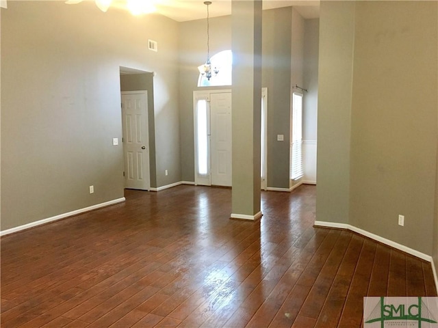 entrance foyer with a towering ceiling, a notable chandelier, and dark hardwood / wood-style floors