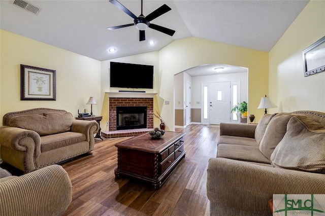 living room featuring ceiling fan, lofted ceiling, dark hardwood / wood-style floors, and a fireplace