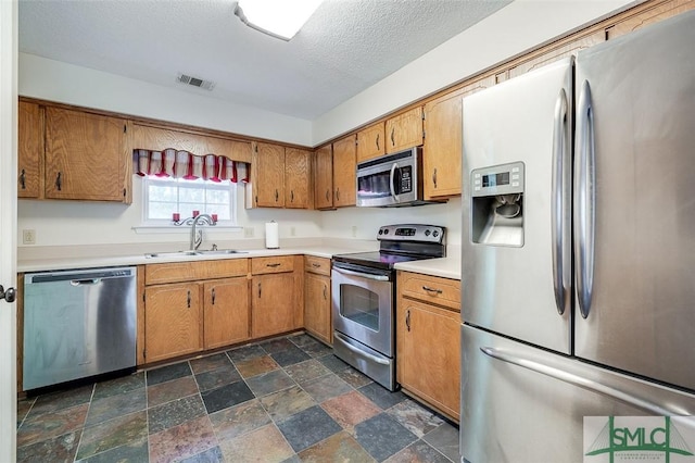 kitchen featuring stainless steel appliances, a textured ceiling, and sink