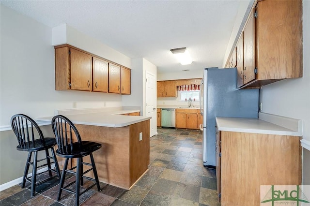 kitchen with a kitchen bar, a textured ceiling, kitchen peninsula, and appliances with stainless steel finishes