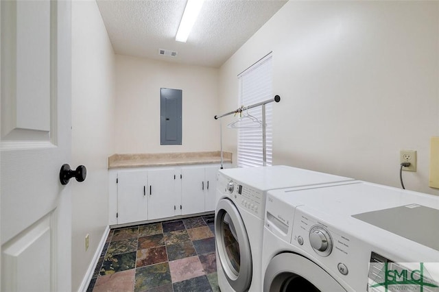 clothes washing area with a textured ceiling, electric panel, cabinets, and separate washer and dryer