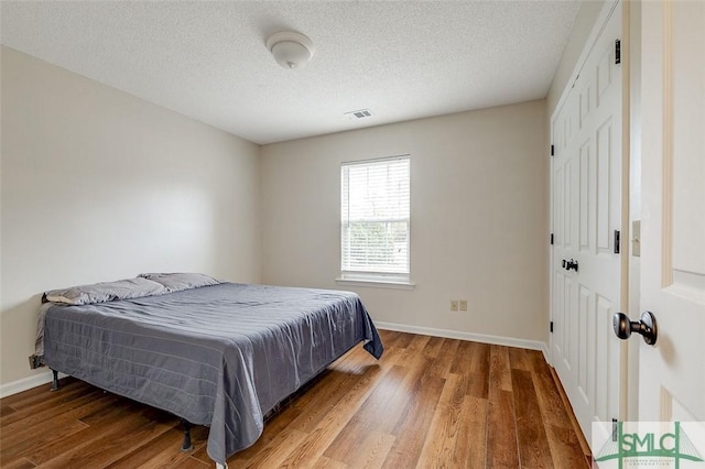 bedroom featuring a closet, wood-type flooring, and a textured ceiling