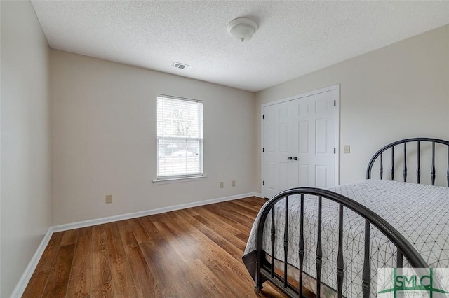 bedroom featuring a closet, hardwood / wood-style floors, and a textured ceiling