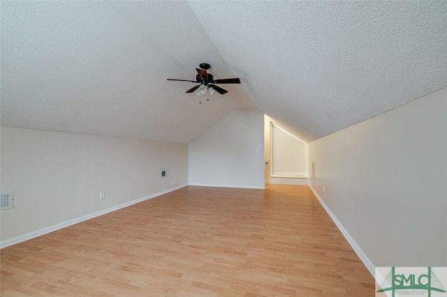 bonus room featuring lofted ceiling, a textured ceiling, ceiling fan, and light hardwood / wood-style flooring