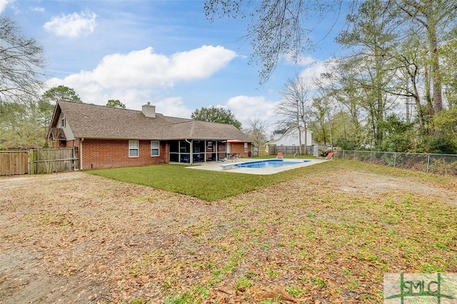 back of house with a yard, a sunroom, and a fenced in pool