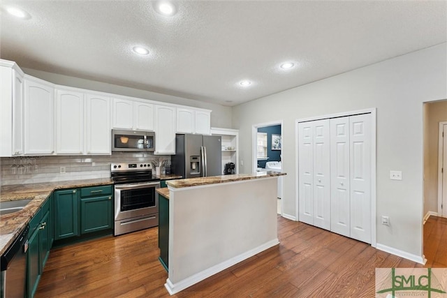 kitchen featuring appliances with stainless steel finishes, white cabinetry, decorative backsplash, dark hardwood / wood-style floors, and green cabinetry