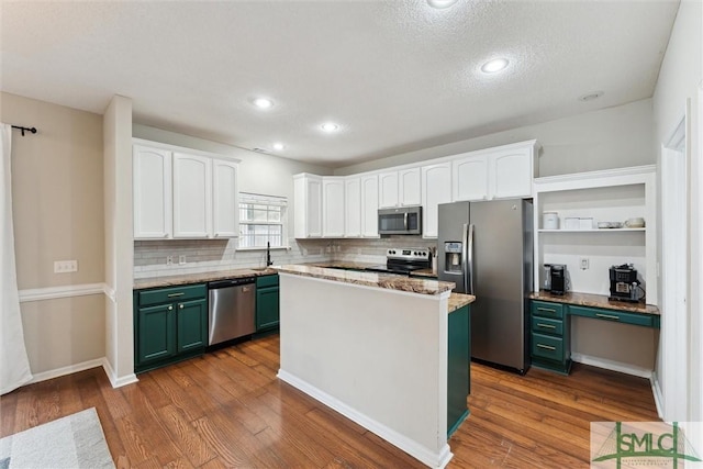 kitchen featuring white cabinets, appliances with stainless steel finishes, a kitchen island, and hardwood / wood-style floors