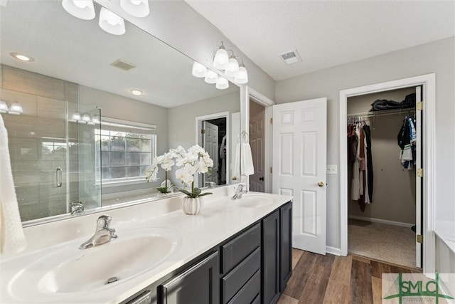 bathroom with vanity, a textured ceiling, hardwood / wood-style floors, and an enclosed shower