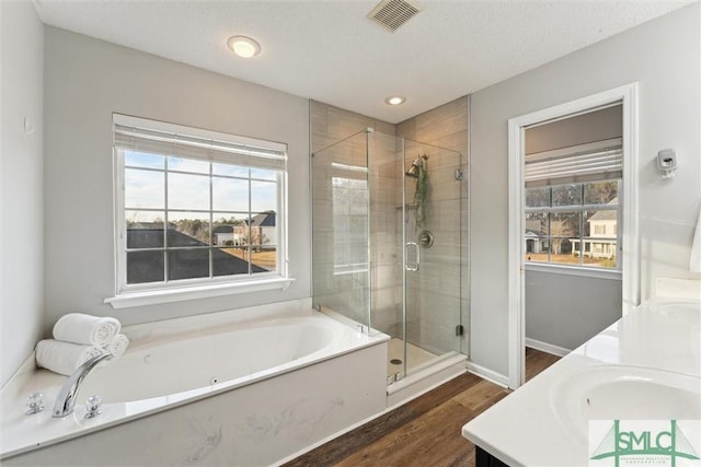 bathroom with a textured ceiling, independent shower and bath, wood-type flooring, and vanity