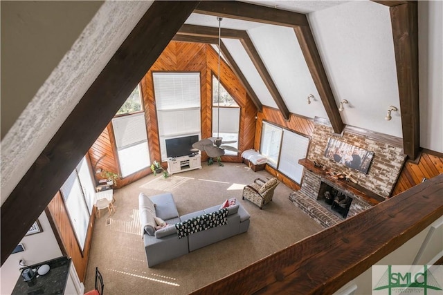 interior space featuring beam ceiling, high vaulted ceiling, wood walls, and a fireplace