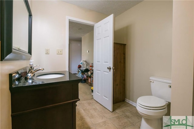 bathroom with a textured ceiling, toilet, vanity, and tile patterned flooring