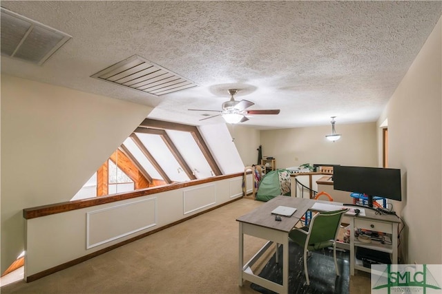 home office with a textured ceiling, ceiling fan, and carpet flooring