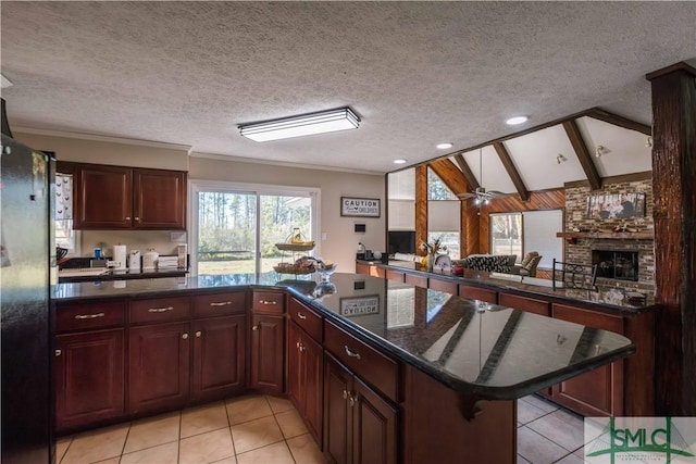 kitchen featuring light tile patterned floors, a kitchen breakfast bar, lofted ceiling, a fireplace, and a textured ceiling