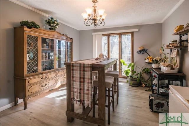 dining space with ornamental molding, an inviting chandelier, a textured ceiling, and light hardwood / wood-style flooring