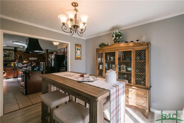 tiled dining space with a textured ceiling, ornamental molding, and a notable chandelier