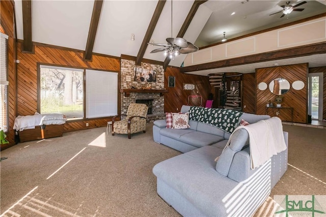 carpeted living room featuring ceiling fan, lofted ceiling with beams, a fireplace, and wood walls