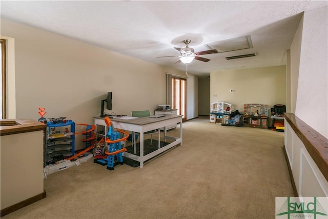 recreation room featuring light carpet, ceiling fan, and a textured ceiling