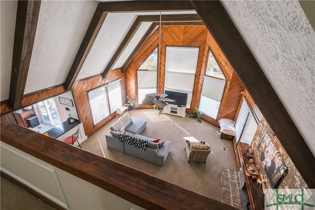 interior space with light carpet, vaulted ceiling with beams, and wooden walls