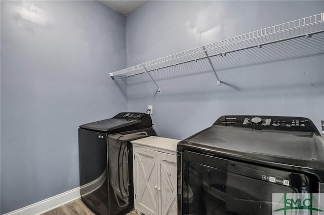 washroom with cabinets, hardwood / wood-style flooring, and washing machine and clothes dryer