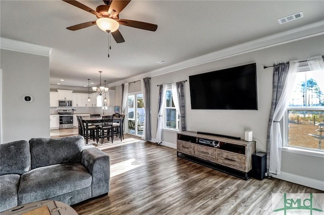 living room featuring hardwood / wood-style floors, crown molding, and ceiling fan with notable chandelier