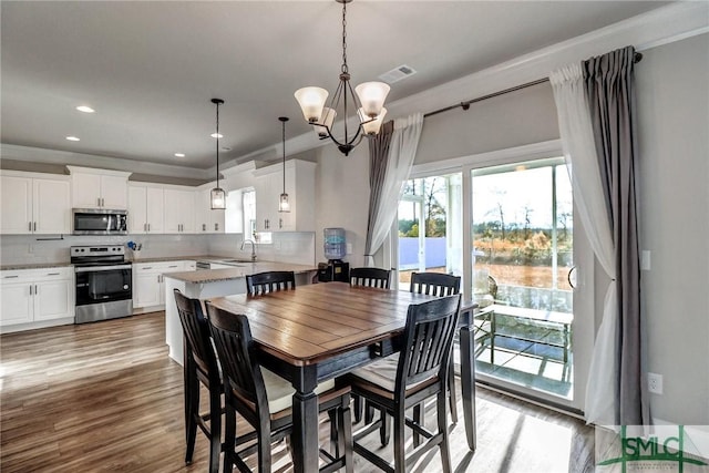 dining area with ornamental molding, light hardwood / wood-style flooring, sink, and a chandelier