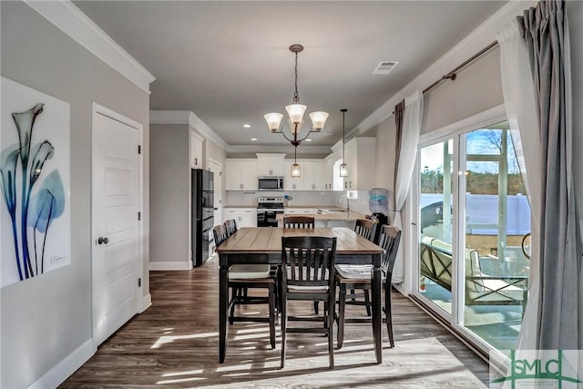 dining area featuring ornamental molding, sink, dark hardwood / wood-style floors, and an inviting chandelier