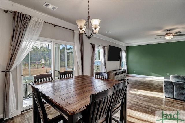 dining area with ceiling fan with notable chandelier, ornamental molding, and light hardwood / wood-style flooring