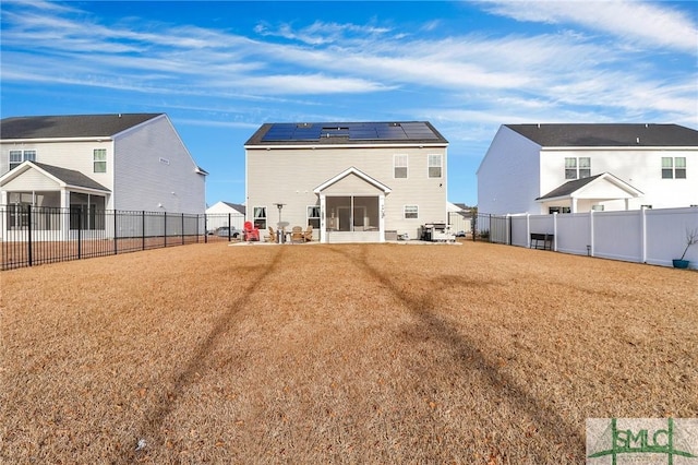 rear view of property with a lawn and solar panels