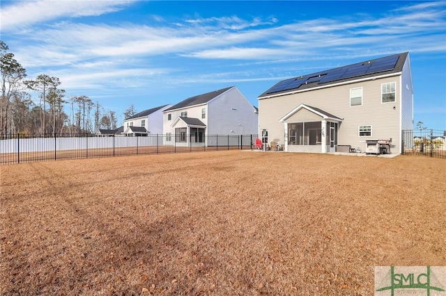 rear view of house with a yard, solar panels, and a sunroom