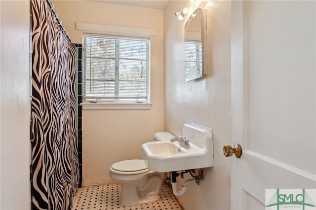 bathroom featuring sink, curtained shower, and toilet