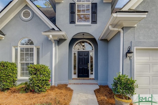 entrance to property with an attached garage and stucco siding