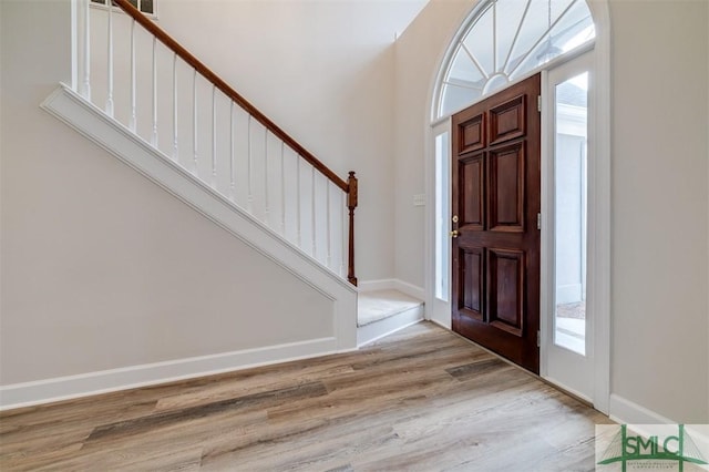 entrance foyer featuring light wood-type flooring, stairs, and baseboards