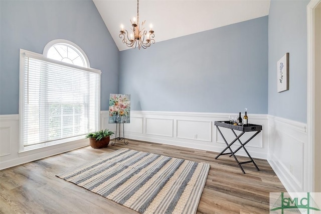 sitting room featuring lofted ceiling, a wainscoted wall, wood finished floors, and an inviting chandelier