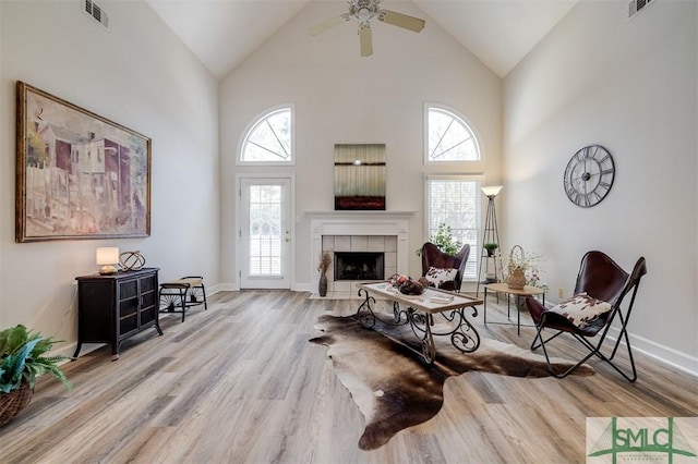 living room with a fireplace, visible vents, a ceiling fan, wood finished floors, and baseboards