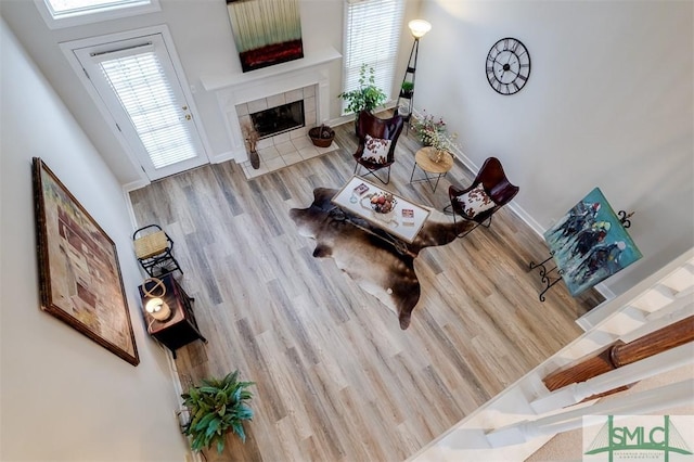 living room featuring baseboards, a tiled fireplace, and wood finished floors