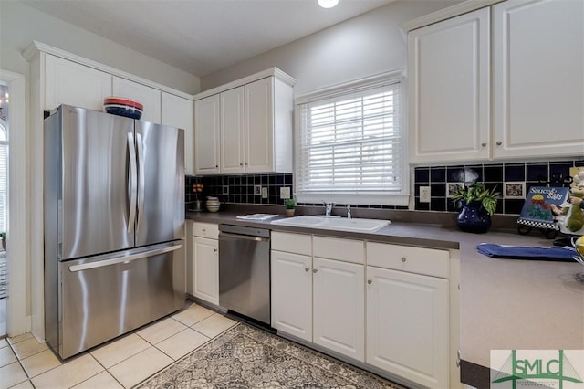 kitchen with light tile patterned floors, a sink, white cabinets, appliances with stainless steel finishes, and dark countertops