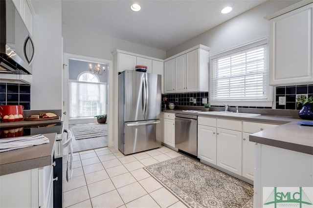 kitchen featuring appliances with stainless steel finishes, white cabinets, a sink, and light tile patterned floors