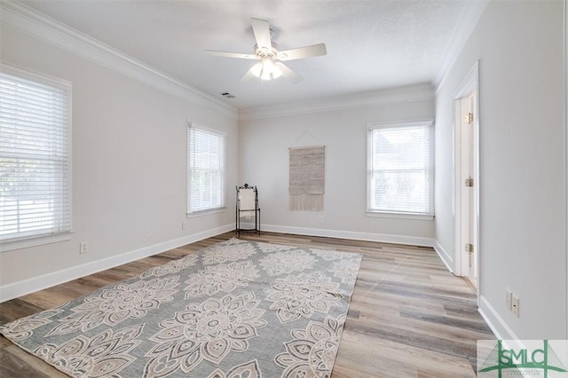 unfurnished room with crown molding, light wood finished floors, visible vents, a ceiling fan, and baseboards